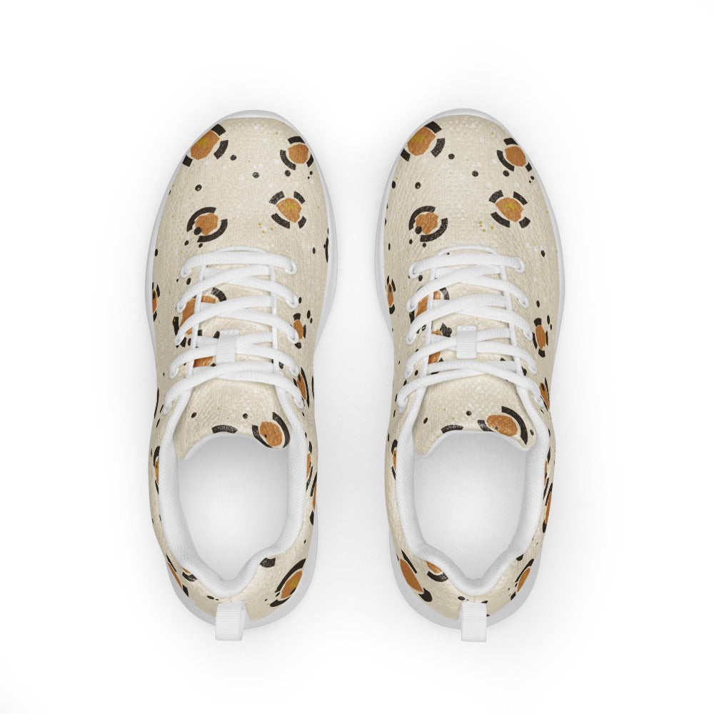 Zapatillas deportivas de mujer con rosetas de pantera caramelo y carbón sobre arena, con coronas doradas escondidas